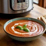 Bowl of creamy vegan tomato basil soup made in the Instant Pot, garnished with basil and coconut cream.
